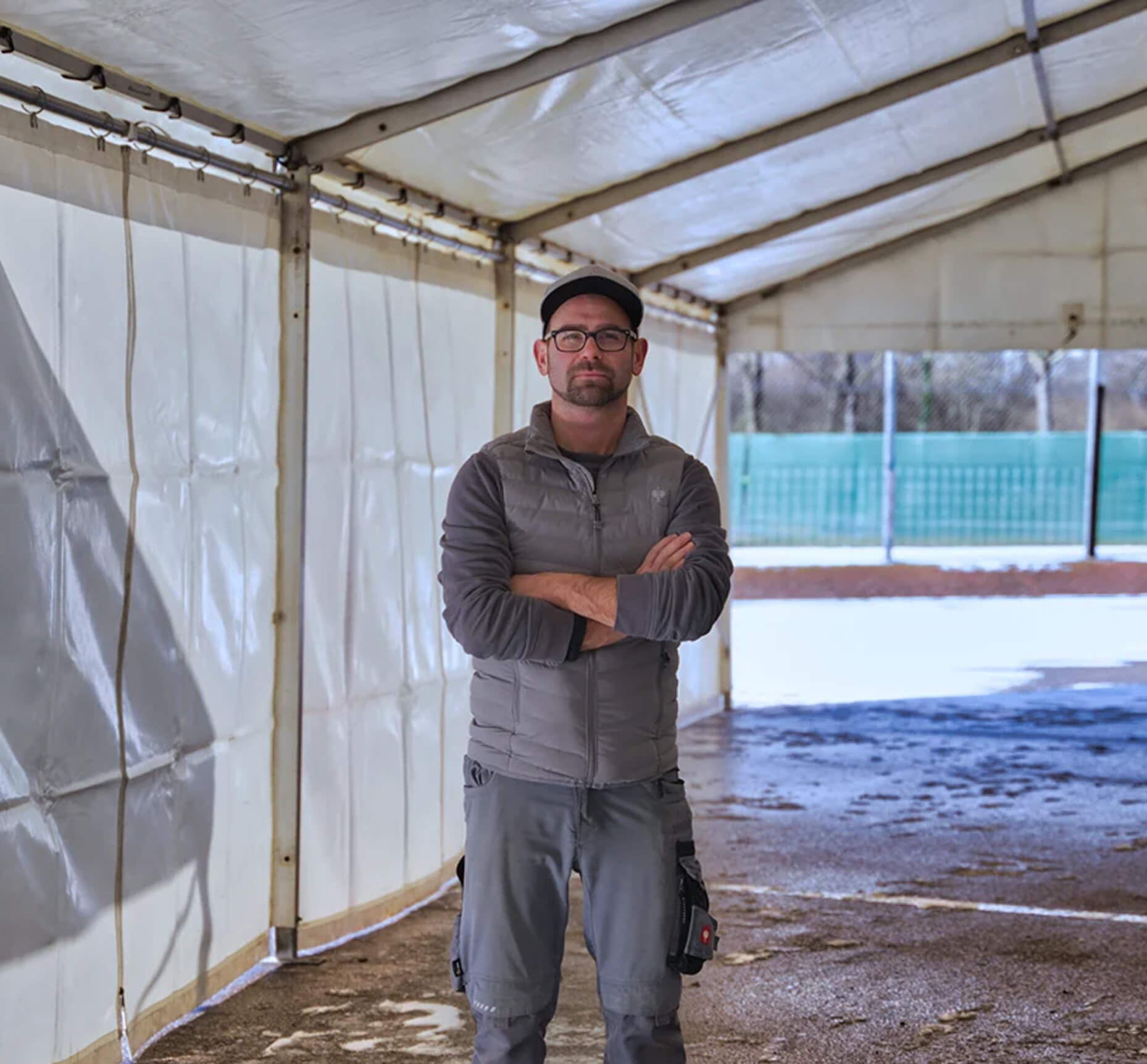 man in workwear standing confidently inside a tent structure