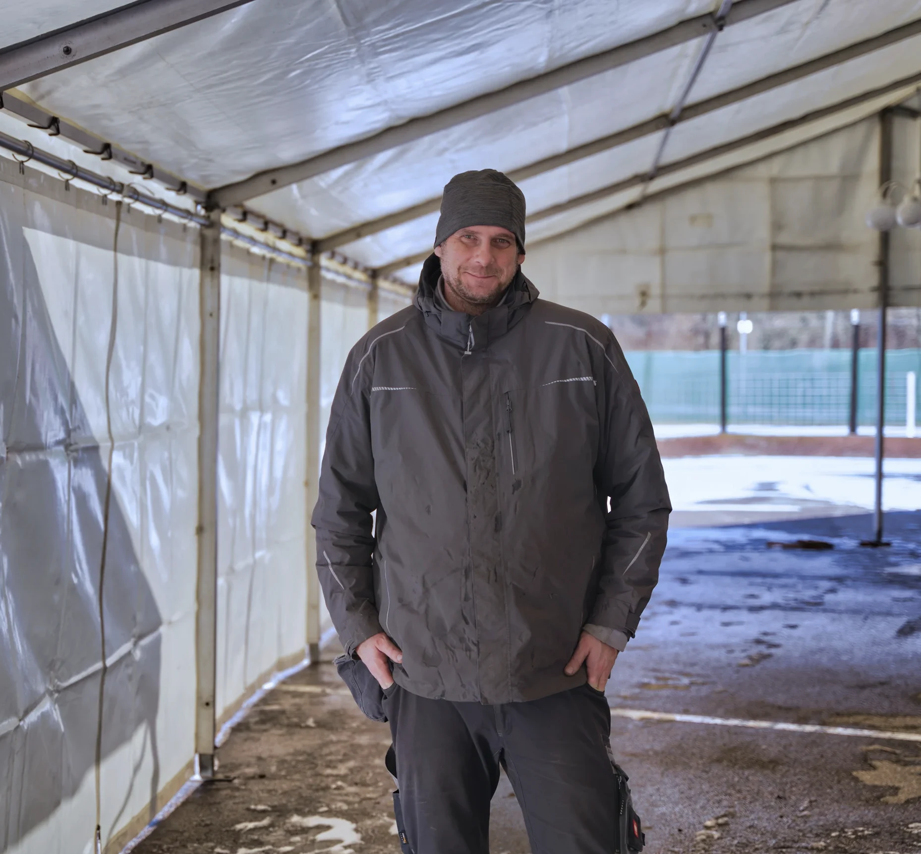 man in winter clothing standing under shelter with snow background